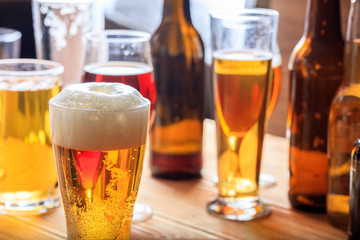 A wooden pub counter, focus on a full frosty glass of beer