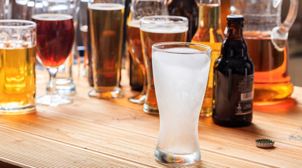 A wooden pub counter, focus on an empty frosty glass of beer