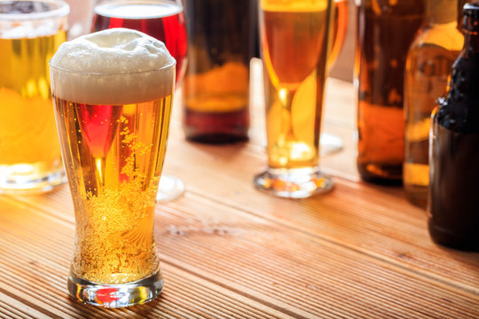 A wooden pub counter, focus on a full frosty glass of beer