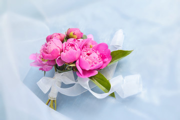Small bouquet of pink peonies on a blue background