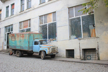 Stara, niebieska ciężarówka na tle starych budynków.