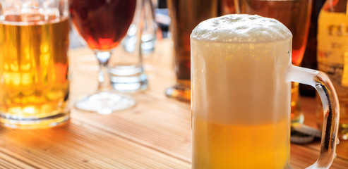 A wooden pub counter, focus on a full frosty mug of beer