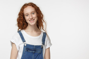 Obraz premium Portrait of smiling attractive curly redhead female isolated on gray background
