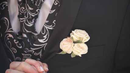Carnation flower in a pocket. the flower in jacket pocket. pin with decorative white flowers pinned on the groom's jacket. boutonniere flower in the pocket of the groom on wedding ceremony