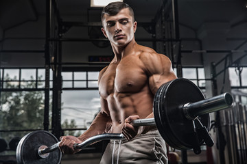 Attractive tall muscular bodybuilder doing heavy deadlifts in moder fitness center.
