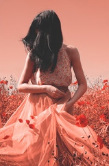 Fototapeta na wymiar Infrared style. Brunette in the poppy flowers field.