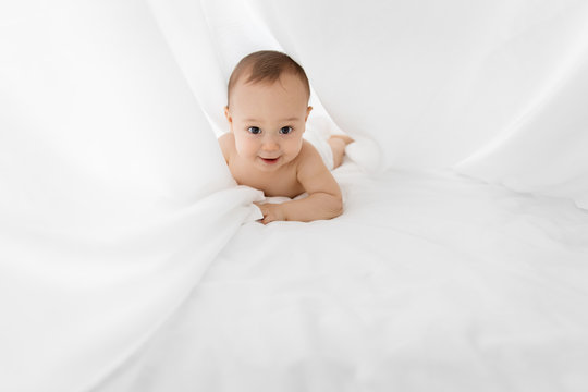 Happy Baby Laying On Tummy Under White Sheet