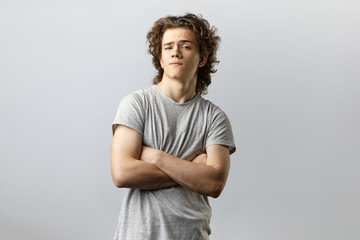 Isolated studio portrait of handsome self confident cool young American posing in studio with arms...