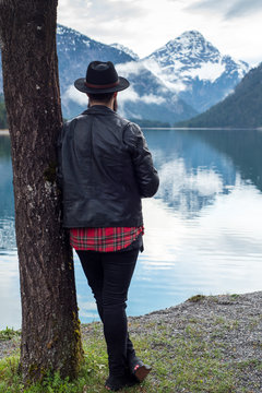 Stylish tattoed Hipster Man enjoys scenic mountain lake in Austria
