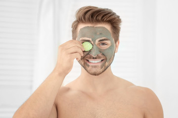 Young man with cosmetic mask on his face in bathroom