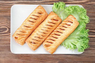 Plate with tasty sausage rolls on wooden table