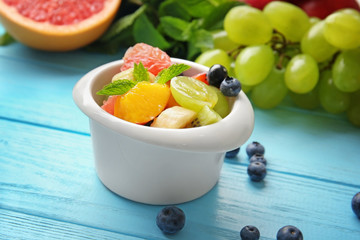 Dish with delicious fruit salad on wooden table
