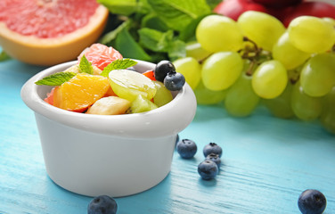 Dish with delicious fruit salad on wooden table