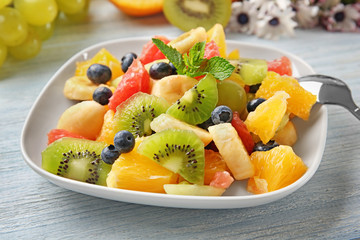 Plate with delicious fruit salad on wooden table