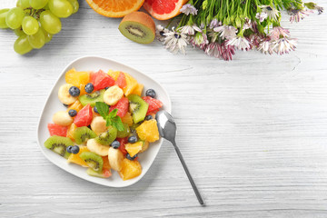 Plate with delicious fruit salad on wooden table