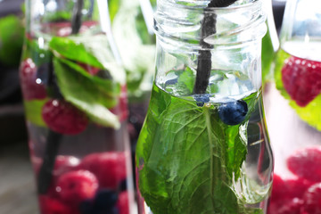Bottles of infused water with berries, closeup