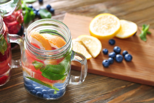 Mason jar of infused water with fruits on wooden table