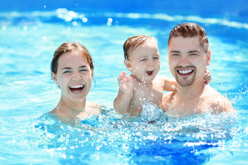 Naklejka premium Child swimming lesson. Cute little boy learning to swim with parents in pool