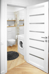 Interior of light modern bathroom with toilet and washing machine