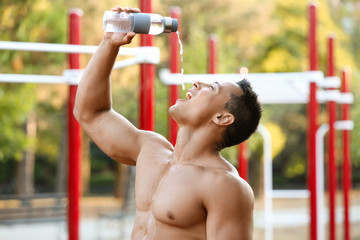 Sporty young man drinking water, outdoors