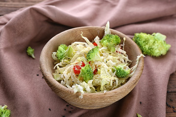 Wooden bowl with tasty vegetable salad on table