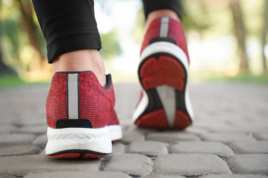 Feet of young woman jogging in park, closeup. Weight loss concept