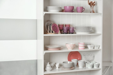Kitchen shelving with dishware on color wall background