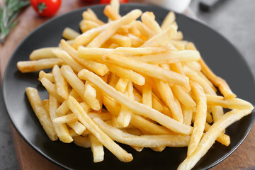 Plate with yummy french fries on table, closeup