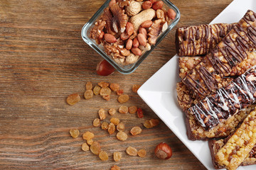 Plate with cereal energy bars and nuts on table