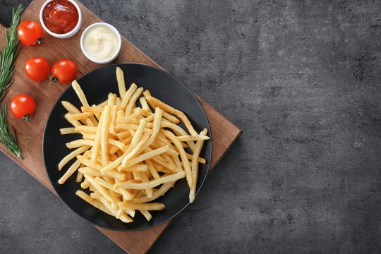 Composition with yummy french fries on grunge background