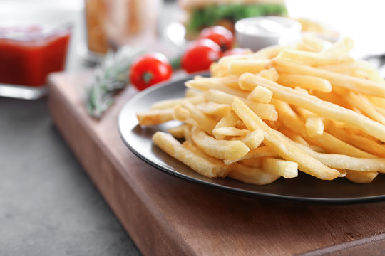 Plate with yummy french fries on table, closeup