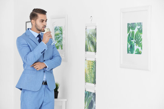 Young man looking at picture of tropical foliage in art gallery
