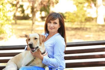 Mature woman sitting with dog on bench outdoors