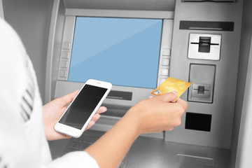 Woman with credit card and cell phone near cash machine, closeup