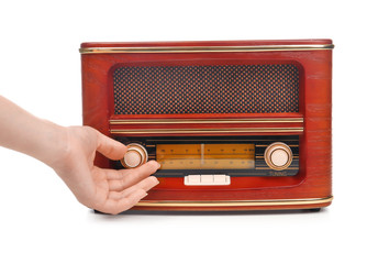 Hand of young woman with retro radio receiver on white background