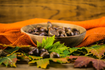 autumn leaf and   chestnuts on  wooden table,