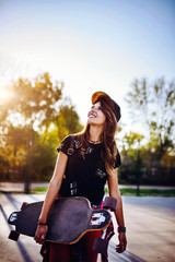 Fototapeta na wymiar Cute urban girl holding skateboard in skatepark - hipster style photo