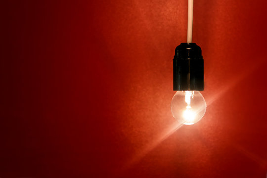 Bright electric bulb on a red background.