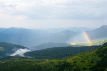 Rainbow and fog in the mountains over the houses