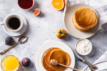 Pancakes with honey, fruit and coffee on a gray background