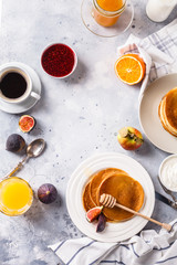 Pancakes with honey, fruit and coffee on a gray background
