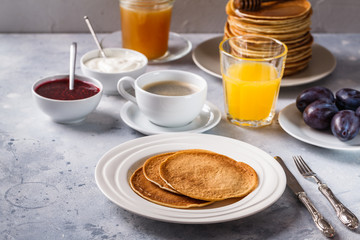 Pancakes with honey, fruit and coffee on a gray background