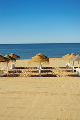 Straw umbrella on relaxing sea beach. Tropical sunny outdoors background.