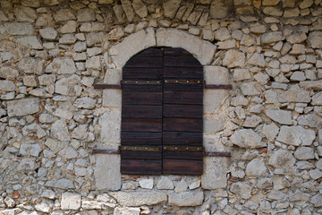 Fototapeta na wymiar antique window shutters made of wood, antique natural stone wall, detail restored house, Central Italy