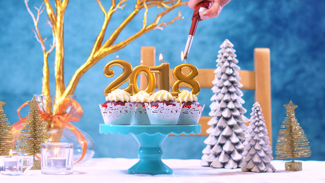 Happy New Year 2018 cupcakes on a modern stylish, festive, blue gold and white Winter theme table setting, lighting candles.