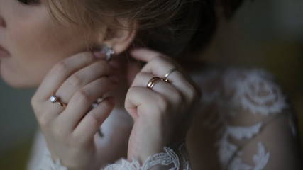 Beautiful bride in puts on earring. Beauty model girl is wearing jewelry for marriage. Wedding...