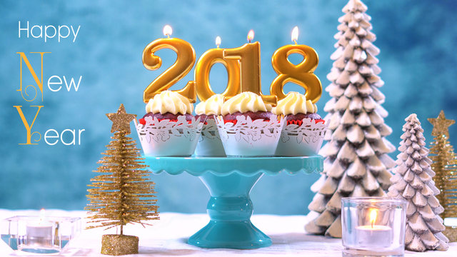 Happy New Year 2018 cupcakes on a modern stylish, festive, blue gold and white Winter theme table setting, close up with Happy New Year text.