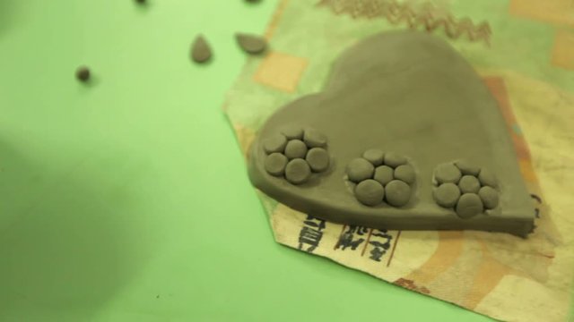 Making souvenirs from clay in an art workshop. A clay heart on a table in an art workshop. Working with clay in art studio.