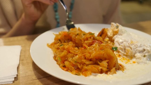 woman eating meatballs with braised cabbage in a ceramic plate. in the cafe. 4k