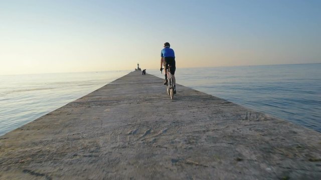 man riding bicycle on pier near the sea port